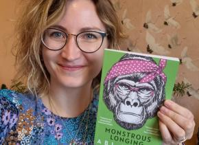 Author Abi Hynes holding up her short story collection Monstrous Longing